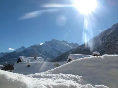 a snow covered roof with the sun in the background at Apartma Maržič in Kranjska Gora