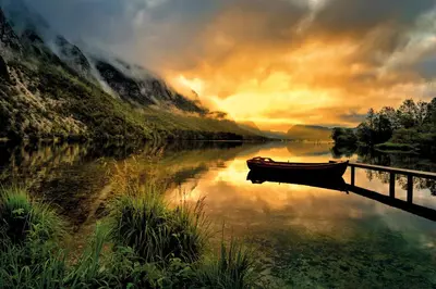 a boat is docked on a river near a bridge at Farmhouse pri Miklavu in Bohinj