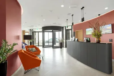 an office lobby with a reception desk and an orange chair at Mond, Resort & Entertainment in Šentilj