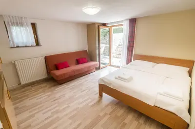 a bedroom with a large bed and a couch at Apartments Henigman in Bohinj