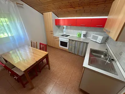 a kitchen with red cabinets and a wooden table at Stres-less Sunny Apartments in Kobarid
