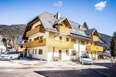 a large building with cars parked in a parking lot at Apartment Katarina Kranjska Gora in Kranjska Gora