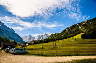 a field with cars parked in front of a mountain at Apartment Katarina Kranjska Gora in Kranjska Gora