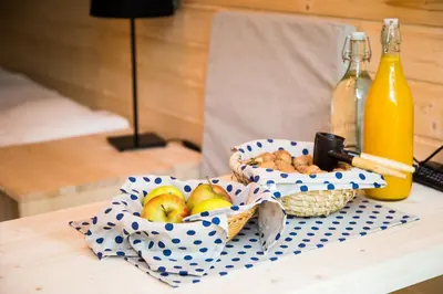 a basket of fruit on a table with a bottle of orange juice at Ribno Alpine Glamping in Bled