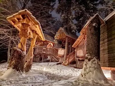 a tree house in the snow in front of a house at Ribno Alpine Glamping in Bled