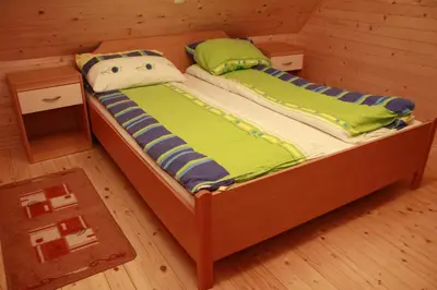 a small bed in a wooden room with at Holiday House Jas-Mar in Radoslavci