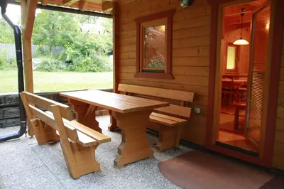 a wooden table and benches on the porch of a cabin at Holiday House Jas-Mar in Radoslavci