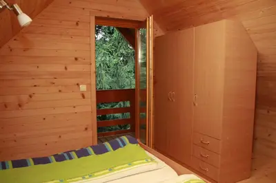 a small bedroom with a bed in a wooden cabin at Holiday House Jas-Mar in Radoslavci
