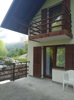 a house with a balcony and a chair on a porch at Apartment Sela in Tolmin