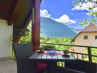 a table on a balcony with a view of a mountain at Bovec Holiday House in Bovec