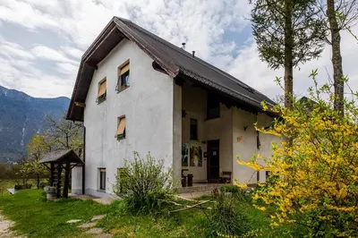 a white house with a gambrel roof at Bovec Holiday House in Bovec