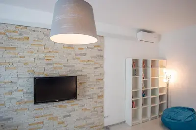 a living room with a tv and a brick wall at Bicycle apartment Ljubljana in Ljubljana
