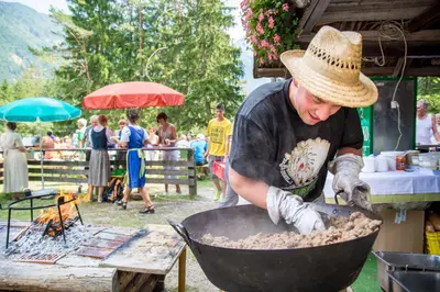 a man is cooking food in a pan at Homestay Kocka in Zgornje Jezersko
