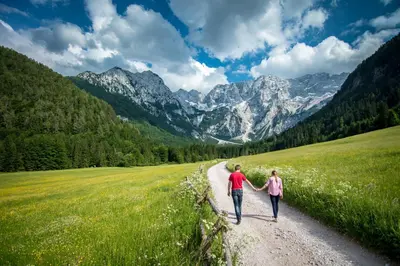 two people walking down a dirt road in the mountains at Homestay Kocka in Zgornje Jezersko