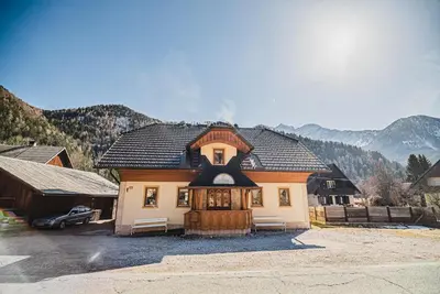 a house with a black roof and a garage at Homestay Kocka in Zgornje Jezersko