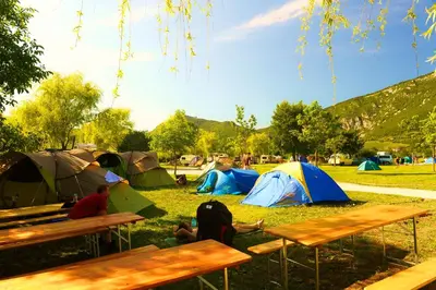 a group of people sitting in the grass with tents at Mobilehouse & Camping Lijak in Šempas