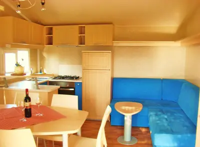 a kitchen with a blue couch and a table in a room at Mobilehouse & Camping Lijak in Šempas
