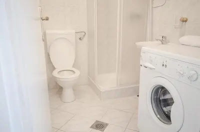 a bathroom with a toilet and a washing machine at Apartment Tržaška with free parking in Ljubljana