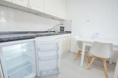 a kitchen with white cabinets and a white table at Apartment Tržaška with free parking in Ljubljana