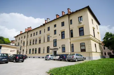 a large building with cars parked in a parking lot at Apartment Tržaška with free parking in Ljubljana