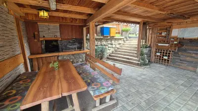 an outside patio with a wooden table and benches at Apartments Čebelica in Bohinj