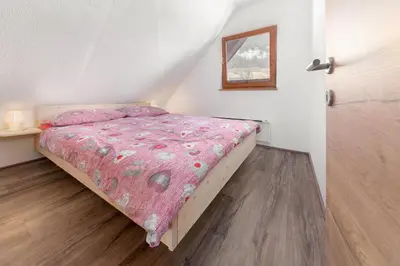 a bedroom with a bed with a pink comforter at Old Mill House in Bohinj