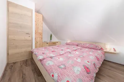 a bedroom with a bed with a pink comforter at Old Mill House in Bohinj