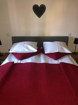 a red and white bed with pillows and a heart on the wall at Apartma Pri Štruklju in Kranjska Gora