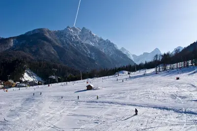 a group of people skiing down a snow covered slope at Apartma Pri Štruklju in Kranjska Gora