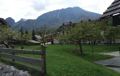 a fence in a green field with mountains in the background at Apartma Pri Štruklju in Kranjska Gora