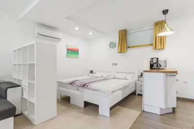 a white bedroom with a bed and a chair at Hisa Taljat in Most na Soči