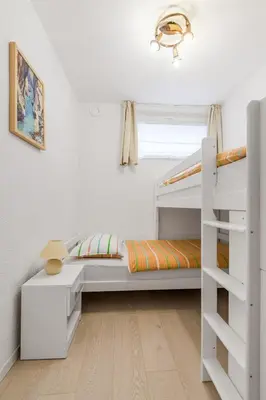 a white bedroom with a bunk bed and a ladder at Hisa Taljat in Most na Soči