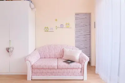a living room with a pink couch with a book on it at Apartma Sara in Bohinj