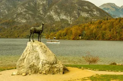a statue of a goat on a rock near a lake at Apartma Sara in Bohinj