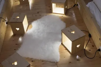 a white rug on a wooden floor with wooden boxes at Brunarica in Bohinj