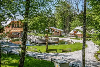 a park with benches and a pond and a house at Slovenia Eco resort in Stahovica