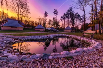 a pond in a park with a bench and a sunset at Slovenia Eco resort in Stahovica