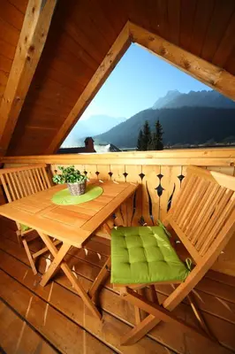 a wooden table and chairs on a porch with a window at Pod Ponco Apartments in Kranjska Gora