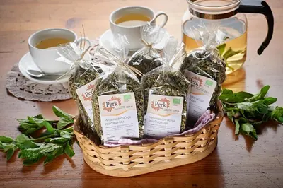 a basket of herbs and cups of tea on a table at Turistična kmetija Perk in Solčava