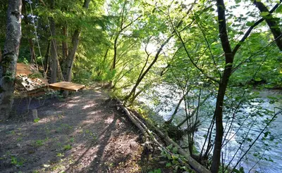 a wooden bench sitting next to a river at Apartma Židan in Kranjska Gora