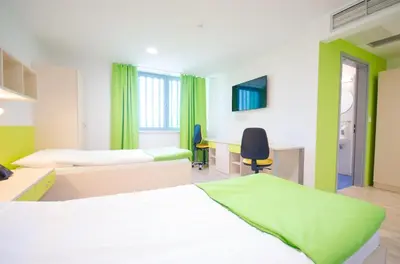a hotel room with two beds and a desk at Sport Hotel Ljubljana in Ljubljana