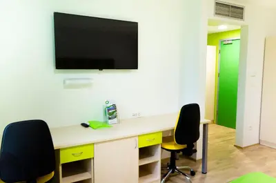 a room with a desk with two chairs and a tv on the wall at Sport Hotel Ljubljana in Ljubljana