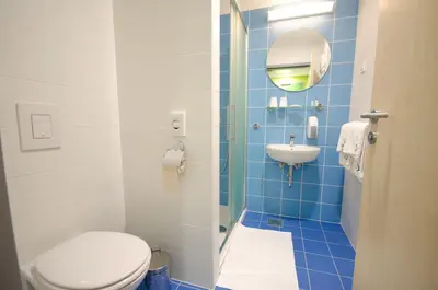 a blue tiled bathroom with a toilet and a sink at Sport Hotel Ljubljana in Ljubljana