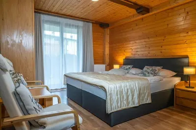 a bedroom with a bed and a wooden wall at Apartment Dijak in Bohinj