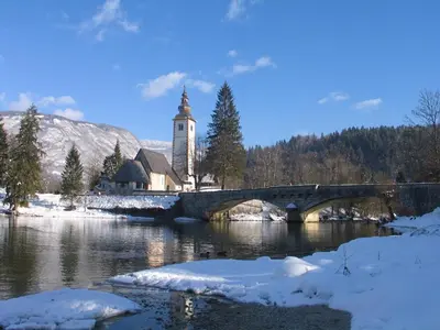 a church with a bridge and a church with a clock tower at Apartment Dijak in Bohinj