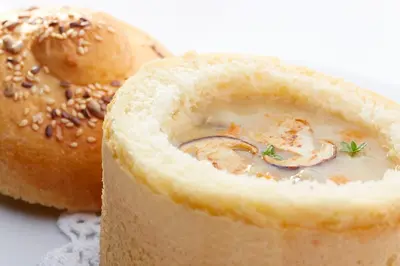 a piece of bread with a bowl of soup next to a bagel at Hotel Delalut in Ravne na Koroškem