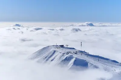 a snow covered mountain with clouds in the background at Hotel Krvavec in Cerklje na Gorenjskem