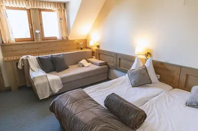 a living room with two beds and a couch at Hotel Krvavec in Cerklje na Gorenjskem