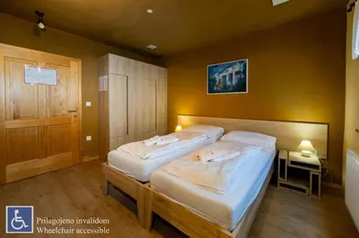 a bedroom with two beds in a room with a door at Youth Hostel Arsviva in Stari Trg pri Ložu