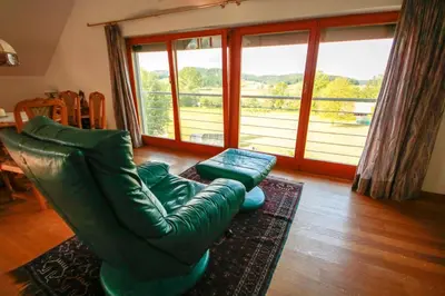 a living room with a green leather couch and a large window at Villa Katarina in Mokronog